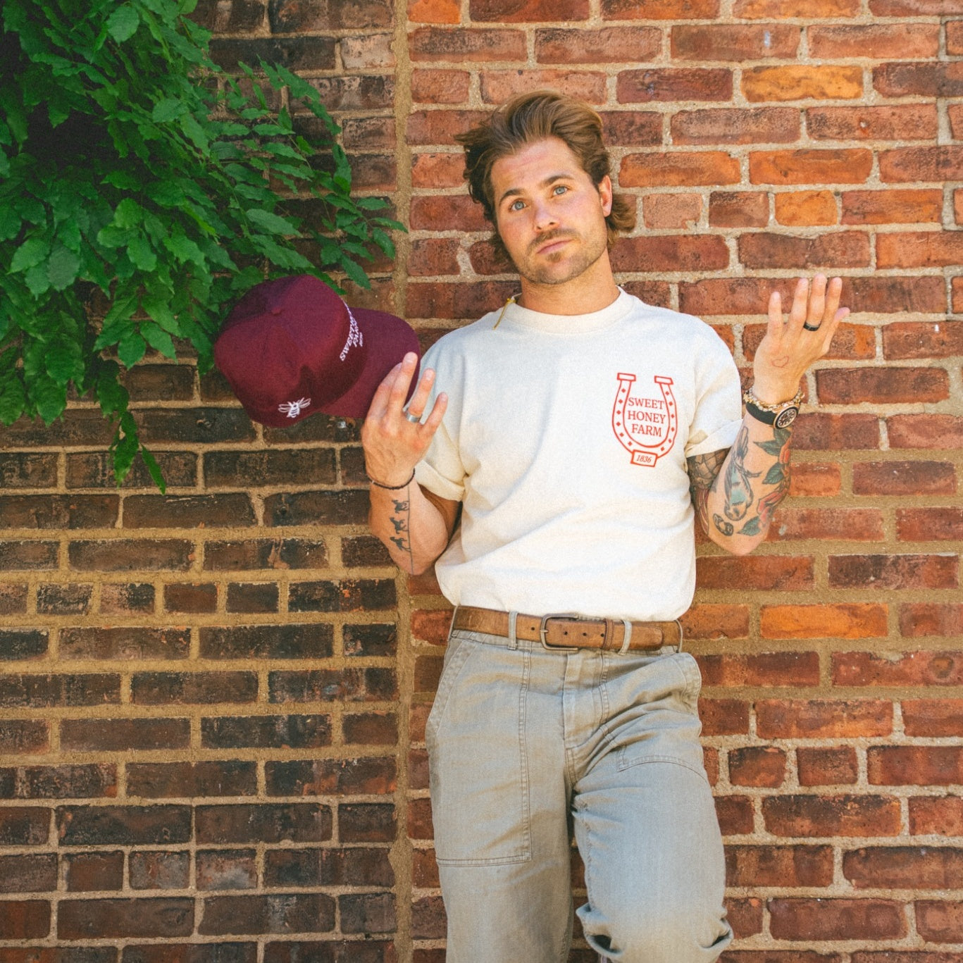Devon Levesque tossing maroon snapback hat with playful expression – Sweet Honey Farm